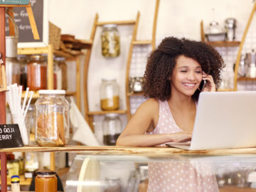 Smiling coffee shop owner researches entrepreneur business loans